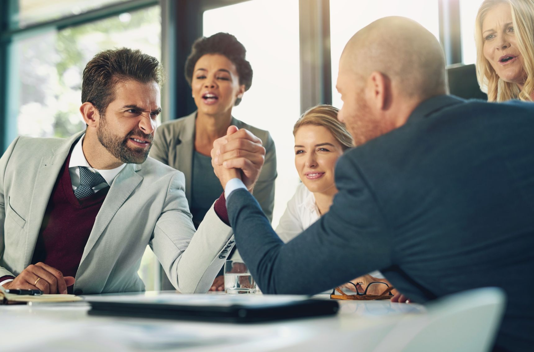 Two colleagues engage in playful arm wrestling, creating a lighthearted moment in the office